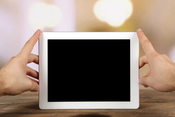 Handen met tablet Pc op houten tafel en licht onscherpe achtergrond — Stockfoto