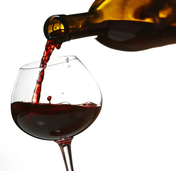 Versare il vino rosso dalla bottiglia in vetro su sfondo colore — Foto Stock