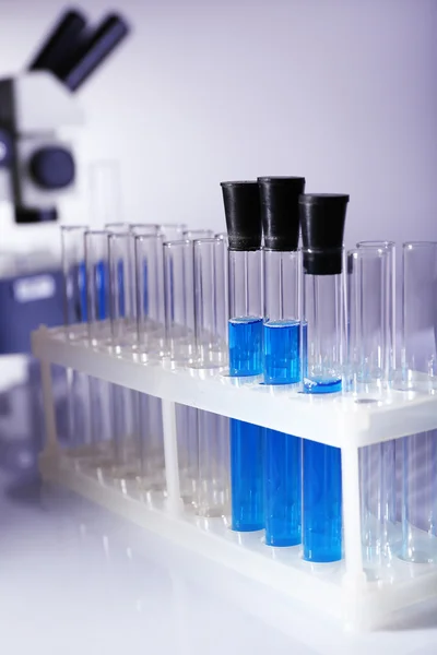 Vetreria da laboratorio con liquido blu su sfondo grigio — Foto Stock