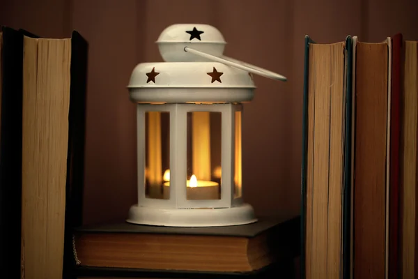 Books and decorative lantern on table and wooden planks background — Stock Photo, Image