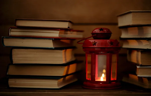 Boeken en decoratieve lantaarn op tafel en houten planken achtergrond — Stockfoto