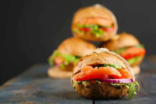 Sandwichs au saumon et légumes sur fond de bois — Photo