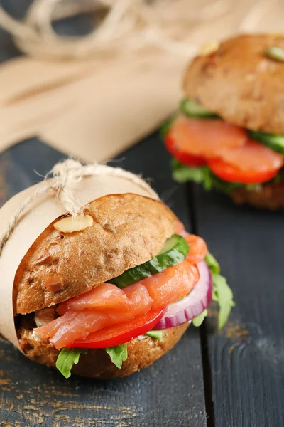 Sandwiches with salmon and vegetables on wooden background — Stock Photo, Image