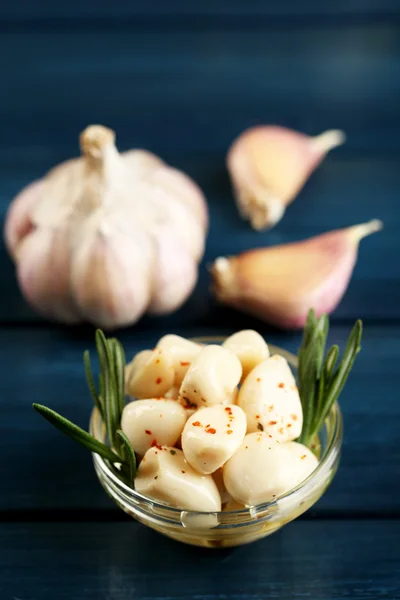 Canned garlic in glass bowl on color wooden background — Stock Photo, Image