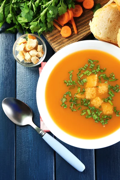 Composition avec soupe aux carottes, ingrédients et herbes sur fond de bois de couleur — Photo