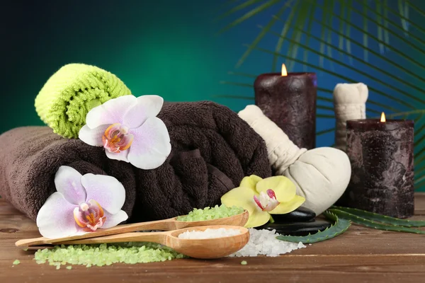 Wellness-Behandlungen mit Orchideenblumen auf Holztisch vor buntem Hintergrund — Stockfoto