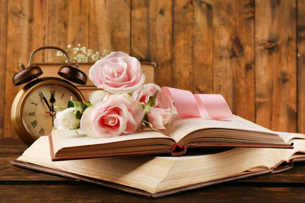 Boeken met bloemen en klok op houten achtergrond — Stockfoto