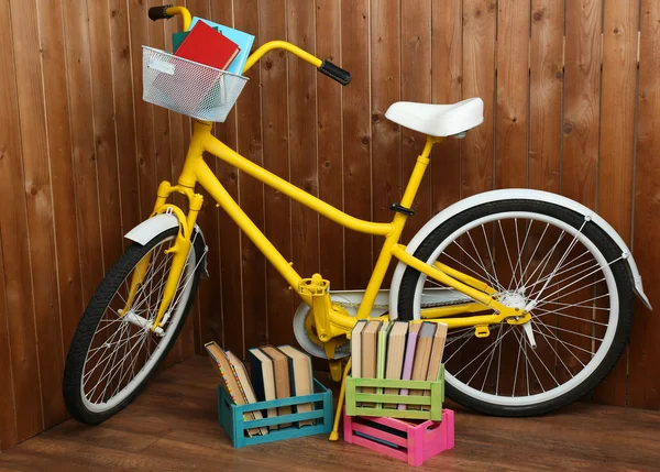 Bicicletta con libri in cassa su fondo parete in legno — Foto Stock