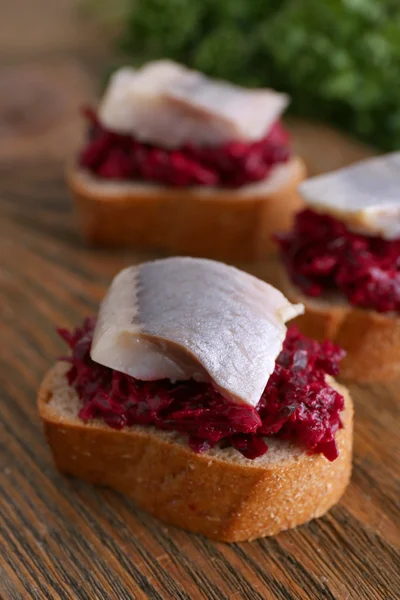 Herring with beets on rye toasts on wooden background — Stock Photo, Image