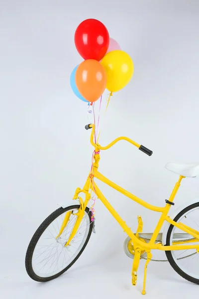 Gelbes Fahrrad mit Luftballons auf weißem Grund — Stockfoto