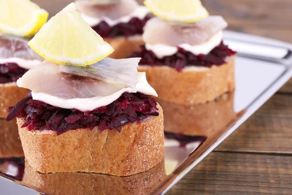 Rye toasts with herring and beets on tray on wooden background — Stock Photo, Image