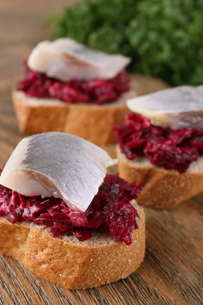 Herring with beets on rye toasts on wooden background — Stock Photo, Image