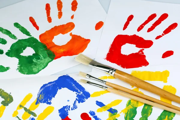 Hand prints of paint and brushes on white background — Stock Photo, Image