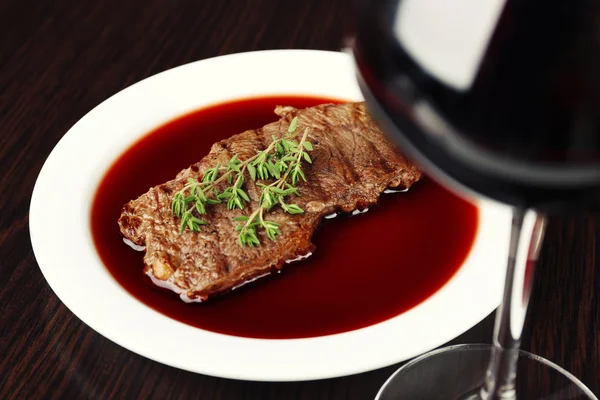 Copo de vinho com bife em fundo de madeira — Fotografia de Stock