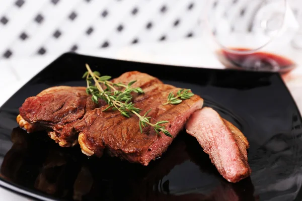 Steak aux herbes sur assiette avec vin sur fond bois — Photo