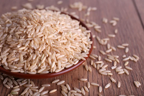 Brauner Reis auf Teller auf Holzgrund — Stockfoto