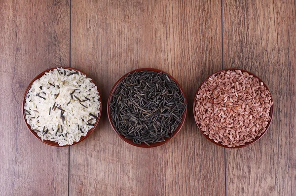 Diferentes tipos de arroz em placas no fundo de madeira — Fotografia de Stock