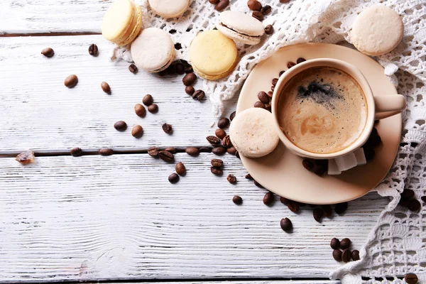 Macarons colorés doux et café en tasse sur fond de bois de couleur — Photo