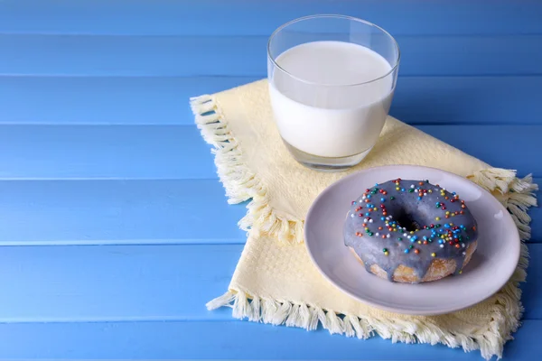 Prosklené kobliha s sklenici mléka na ubrousek a barevné dřevěné pozadí — Stock fotografie