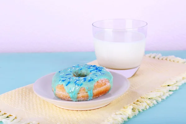 Donut vitrificado com vidro de leite em guardanapo e cor de fundo de madeira — Fotografia de Stock