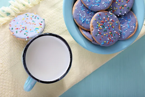 Πλάκα Μπισκότα εφυαλωμένη και κούπα του γάλακτος σε χαρτοπετσέτα και χρώμα φόντο ξύλινο τραπέζι — Φωτογραφία Αρχείου
