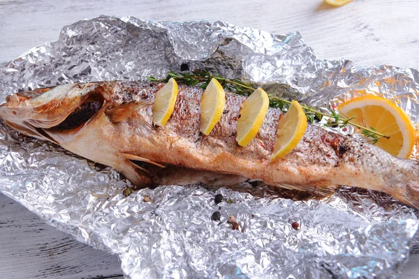 Sabroso pescado al horno en papel de aluminio en primer plano de la mesa — Foto de Stock