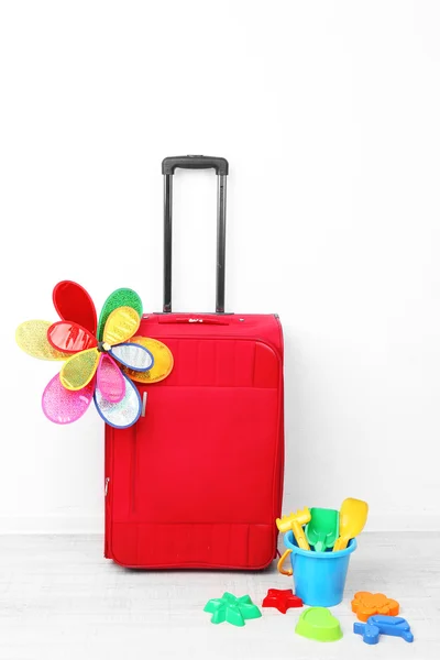 Red suitcase with toy flower and child toys isolated on white — Stock Photo, Image