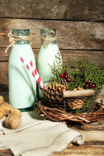 Botellas de leche fresca con decoración natural, sobre fondo de madera — Foto de Stock