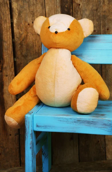 Brinquedo de urso na cadeira no fundo de madeira — Fotografia de Stock
