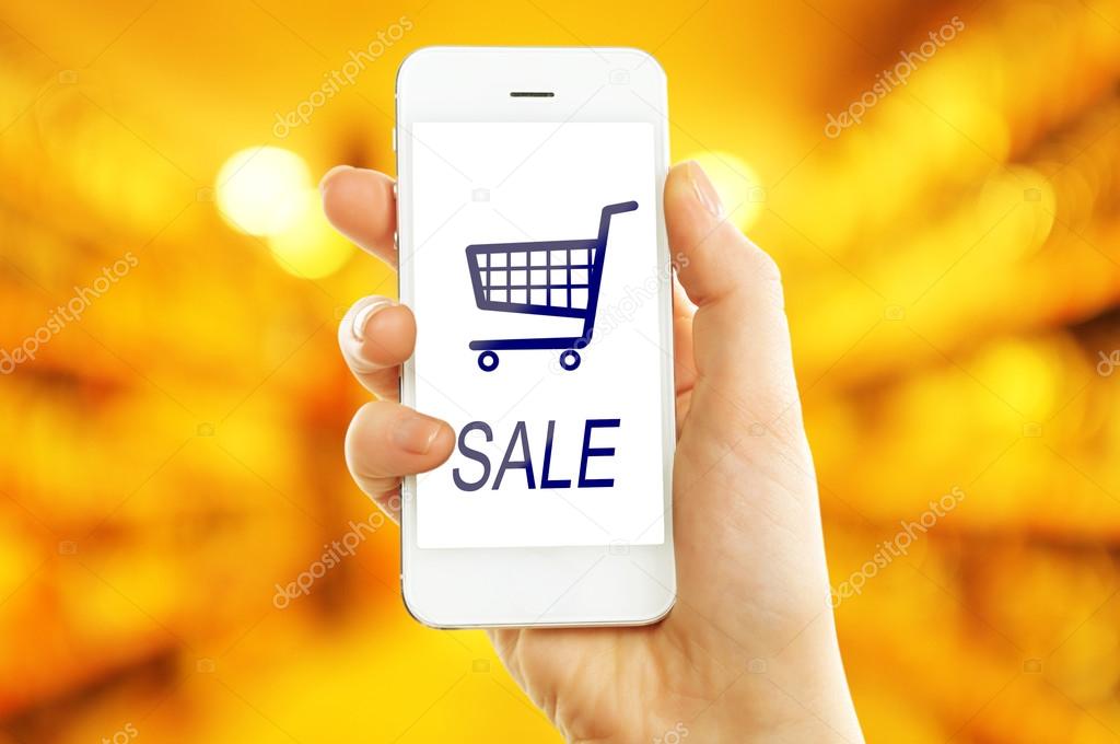 Mobile shopping concept. Hand holding mobile phone for internet shopping on supermarket background