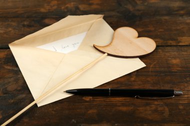 Kalp ve rustik ahşap masa arka plan üzerinde kalem ile zarf