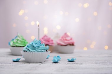 Lezzetli doğum günü kek ışık arka plan üzerinde masada