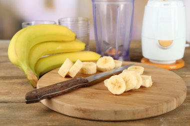 Parlak zemin üzerine ahşap masa üzerinde kesme tahtası üzerinde muz dilimlenmiş