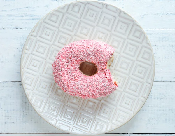 Bitten delicious donut on plate on wooden table close-up — Stock Photo, Image