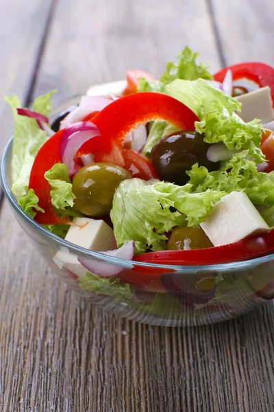 Griekse salade in glas schotel op houten tafel achtergrond — Stockfoto
