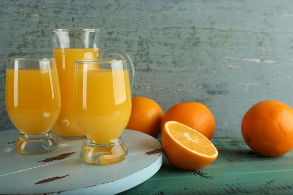 Glas Orangensaft mit Scheiben auf farbigem Holzhintergrund — Stockfoto