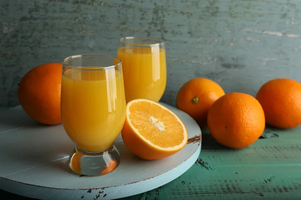 Sklenice pomerančové šťávy s výsečí barevné dřevěné pozadí — Stock fotografie