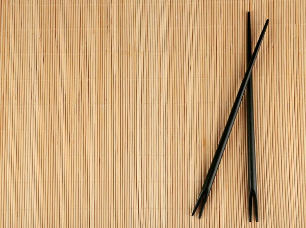 Pair of chopsticks on light bamboo mat background — Stock Photo, Image