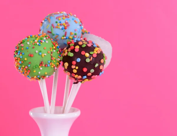 Söta cake pops i vas på rosa bakgrund — Stockfoto