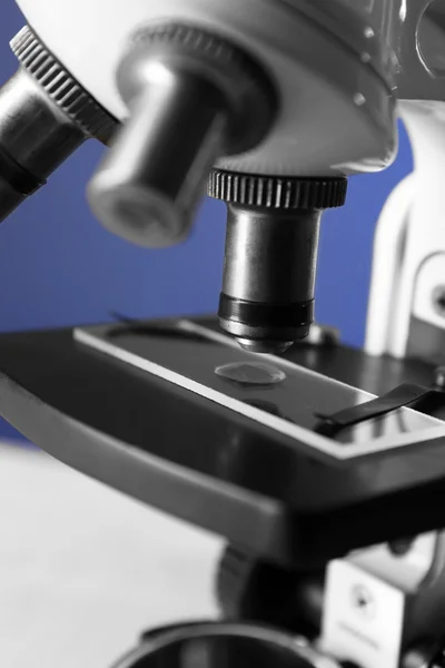Microscoop op tafel, op een achtergrond met kleur, close-up — Stockfoto