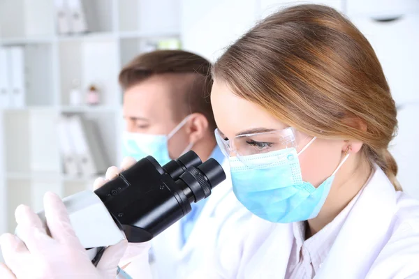 Científicas jóvenes y masculinas con microscopio en laboratorio —  Fotos de Stock