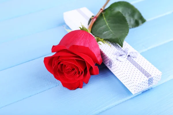 Красивая красная роза с подарочной коробкой на фоне деревянных досок — стоковое фото