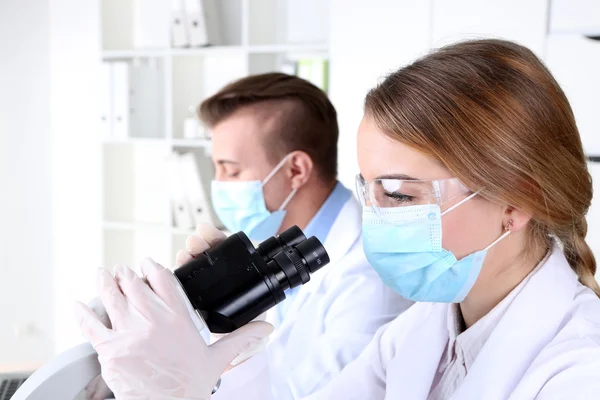 Científicas jóvenes y masculinas con microscopio en laboratorio — Foto de Stock