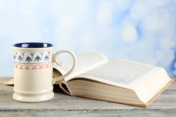 Xícara de chá e livro na mesa, no fundo brilhante — Fotografia de Stock