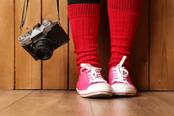 Flicka i sneakers med retro kamera — Stockfoto