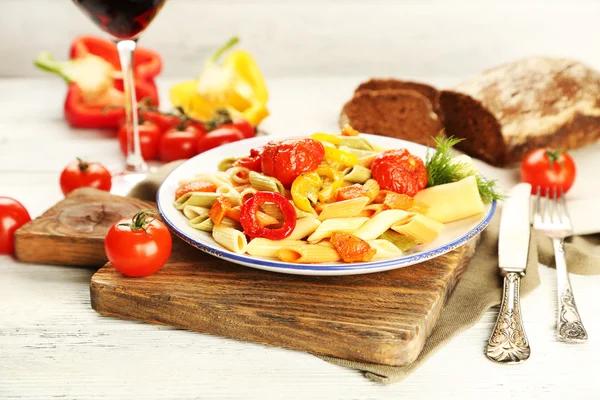 Pasta salad with pepper, carrot and tomatoes on wooden table background — Stock Photo, Image