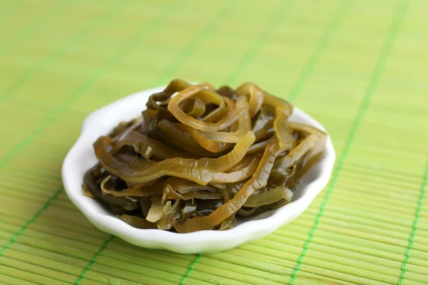 Seaweed in white bowl on bamboo mat background — Stock Photo, Image