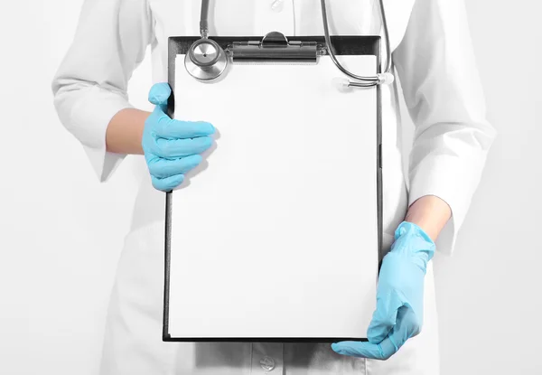 Arzt hält Klemmbrett auf hellem Hintergrund — Stockfoto