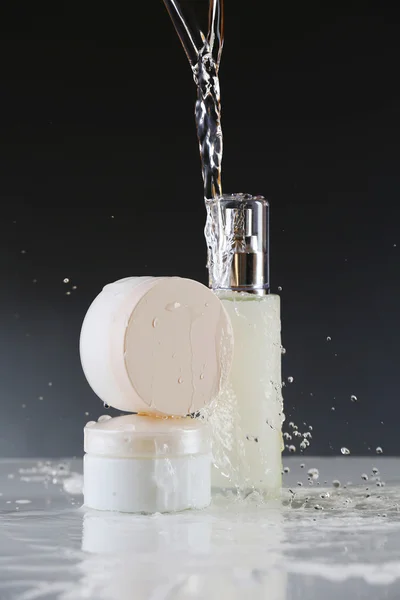 Cosmetic products in water splashes — Stock Photo, Image