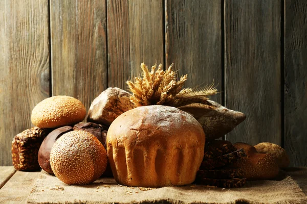 Different bread on table on wooden background — Stock Photo, Image